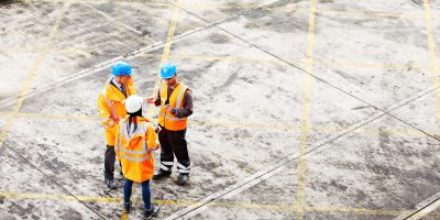 High angle shot of three workers talking together while standing on a commercial dock